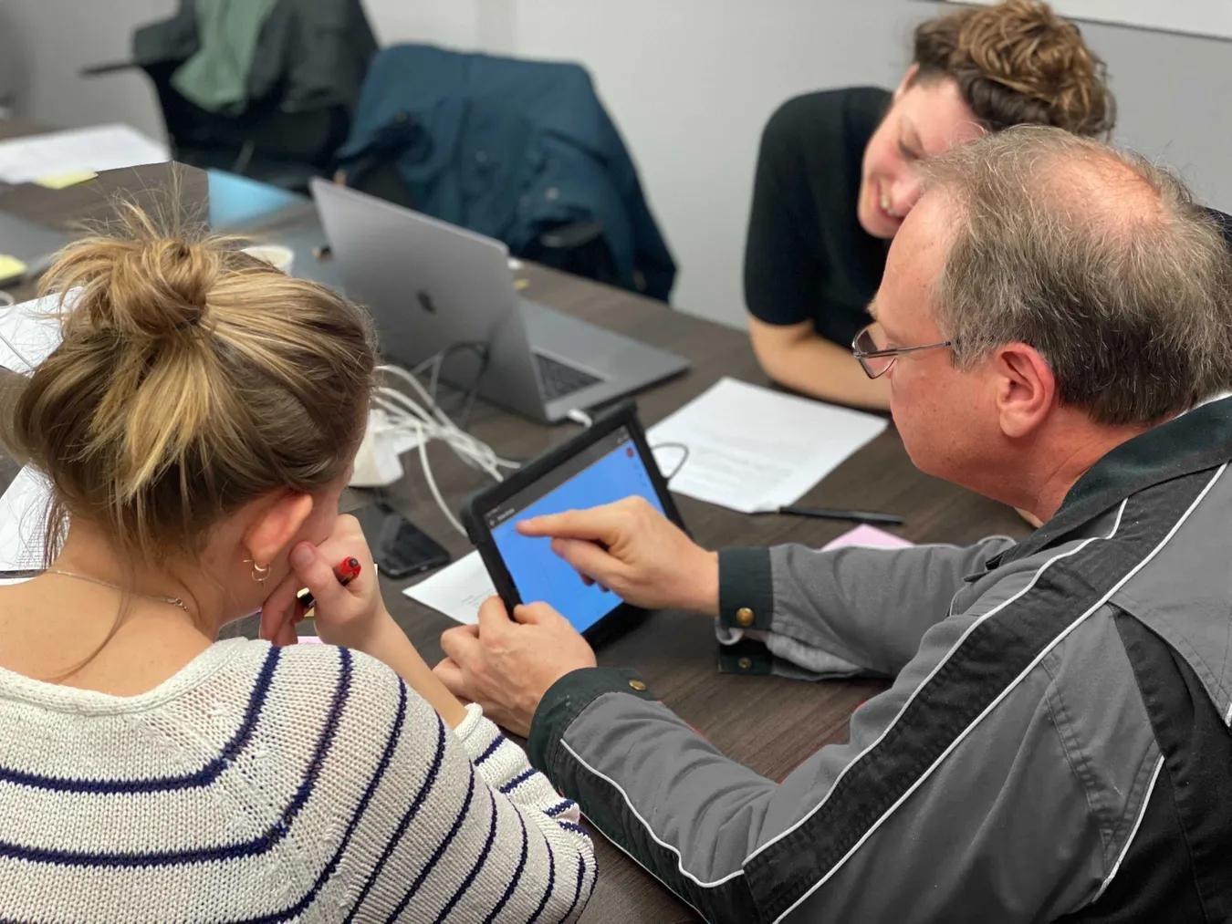 Two people in a user test, in which one subject performs the test on a tablet.