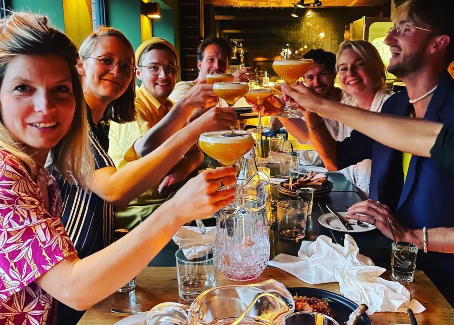 Aantal humanoids zitten aan tafel en proosten met cocktails